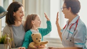A smiling doctor in a white coat high-fives a young child