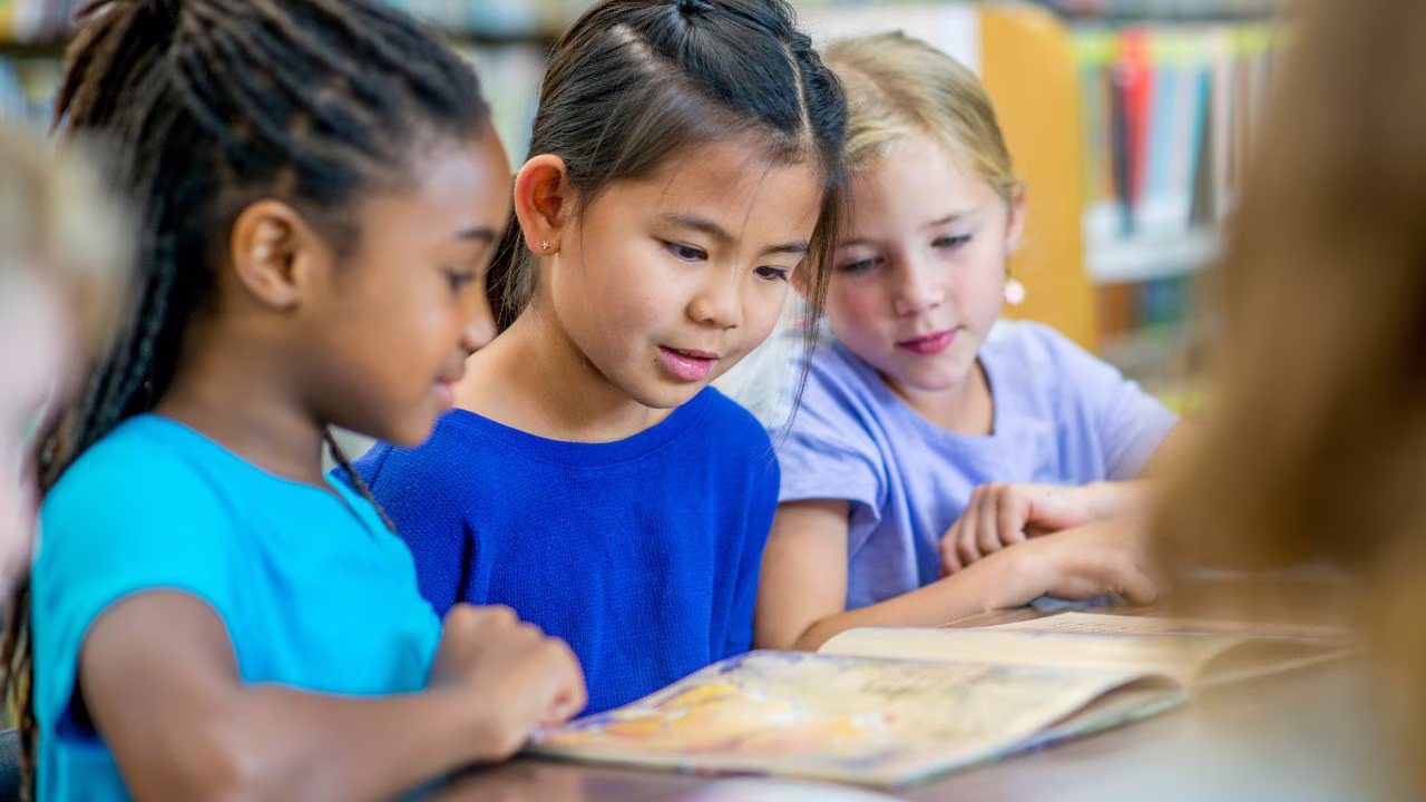 Three students reading a book together