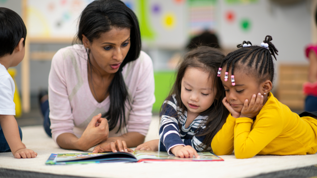 Teacher with students reading a book.